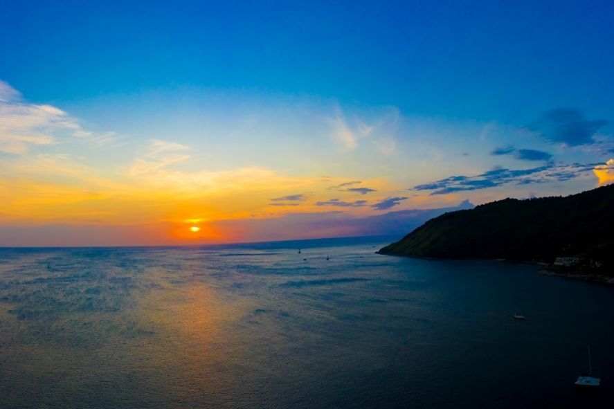 sunset over nai harn beach with calm water